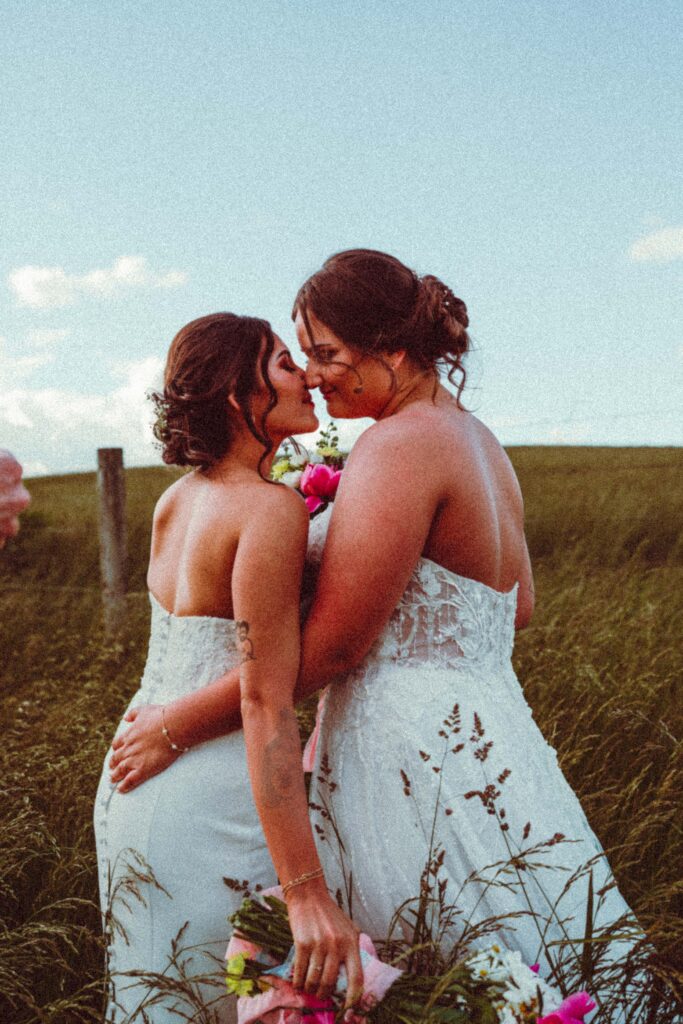 Lesbian couple holding hands in tall grass, styled editorial wedding portrait in Pennsylvania