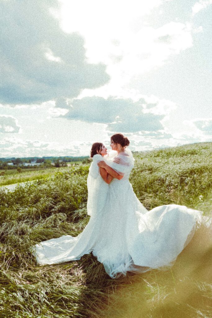 Two brides walking together through tall grass during a nontraditional wedding photo session in Pennsylvania