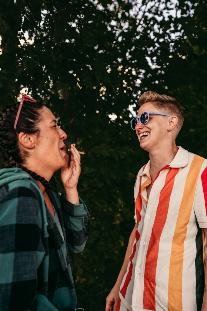 Nontraditional queer couple relaxing together on the beach during their wedding day, photographed with an editorial documentary approach