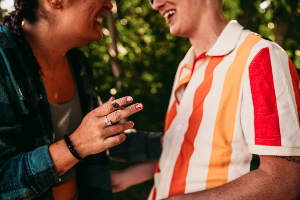 Queer couple sitting together on the beach during their wedding day, sharing a quiet, intimate moment at sunset