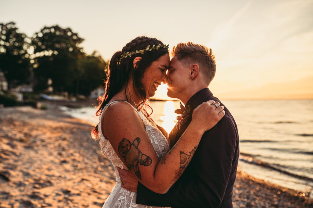 Nonbinary and queer couple sharing a kiss at sunset on the beach, elopement photography in Pittsburgh